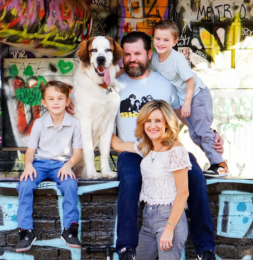 Family portrait with three children, parents, and a large St. Bernard in front of a graffiti wall