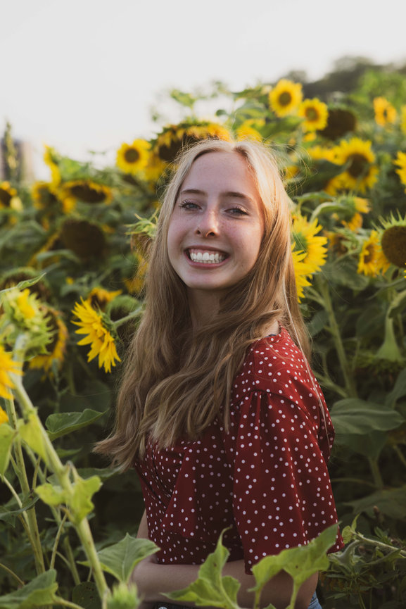 high school senior girl in sunflower field with big smile