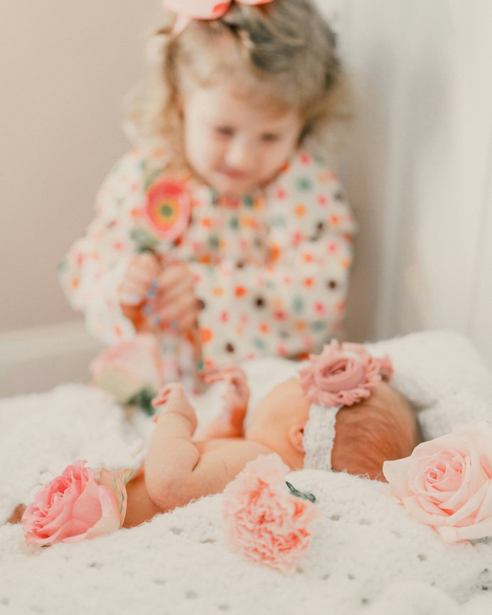 Little girl looking at a newborn baby on a blanket