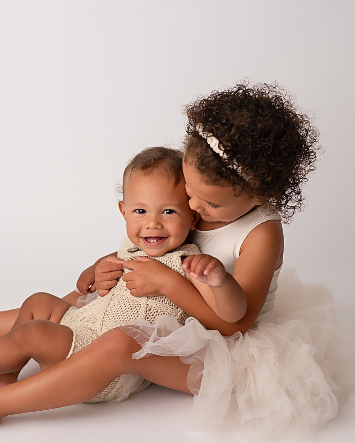 Toms River brother and sister cuddled together in white studio