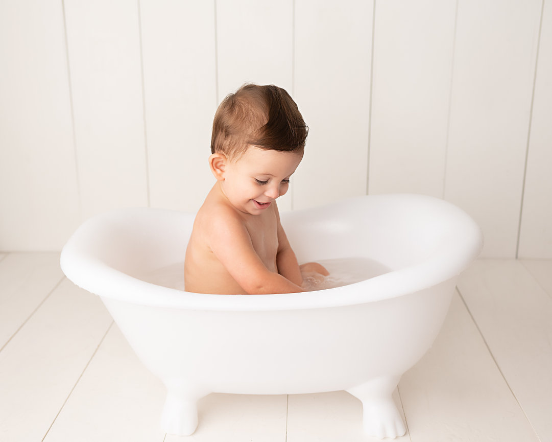 Baby splashing while rinsing off frosting in vintage bathtub in East Brunswick, NJ