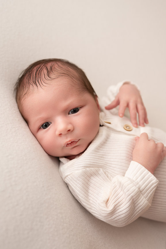Soft moment of baby naturally posed on neutral backdrop