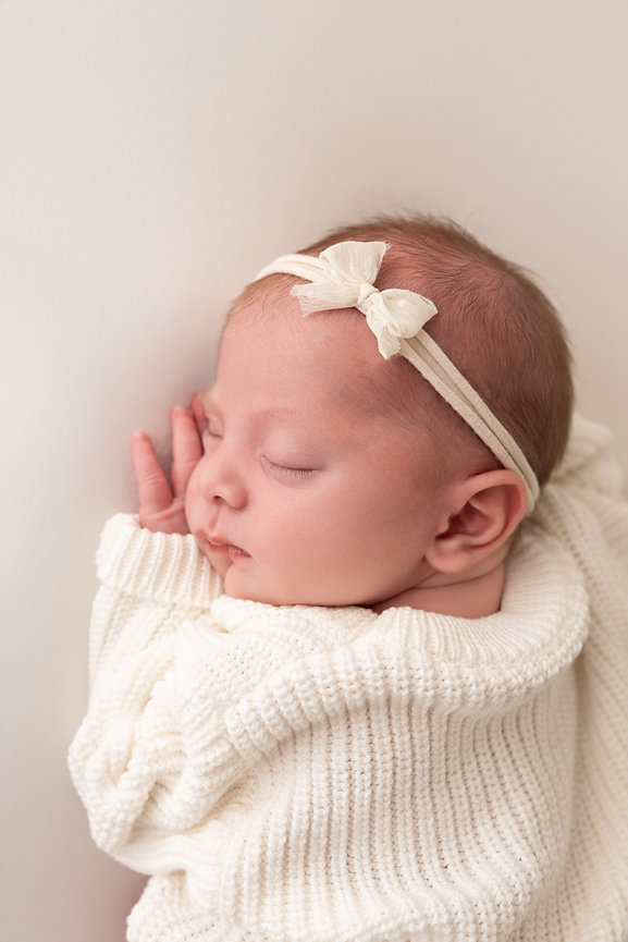 Baby’s soft cheek pressed into white backdrop in Scotch Plains clean, minimalist studio