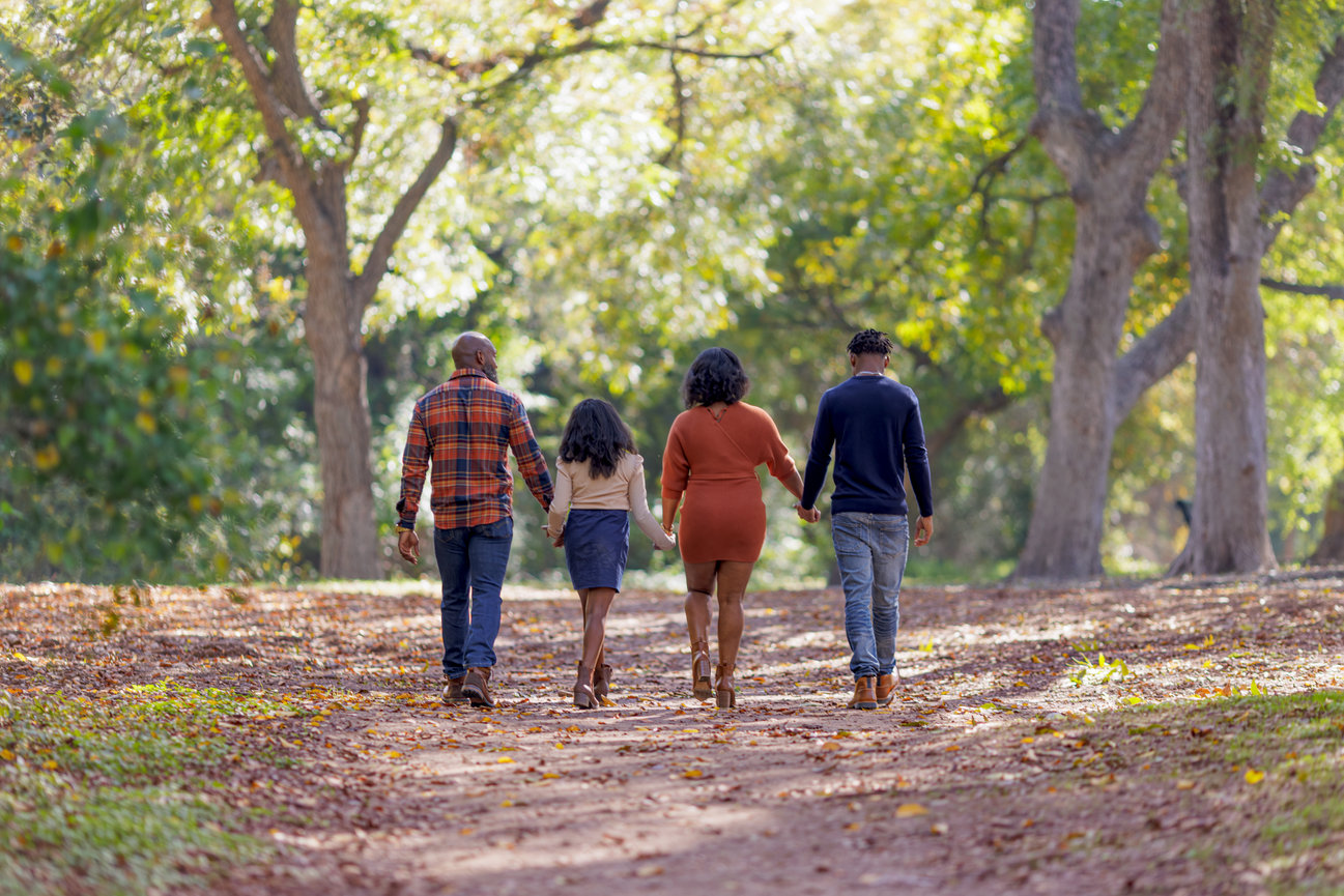Family walking hand-in-hand on a scenic, tree-lined path in autumn at Breckenridge Park in Richardson, TX