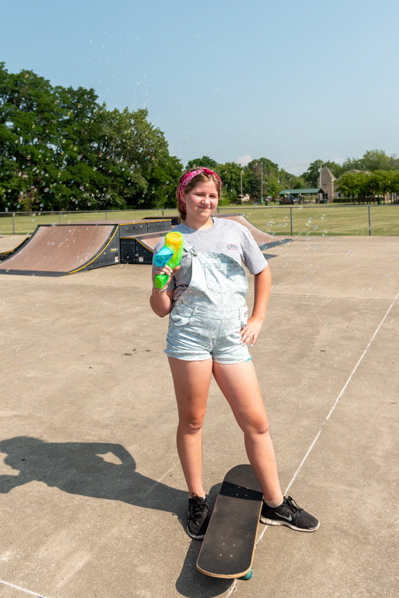 Girl holding a drink while standing on a skateboard
