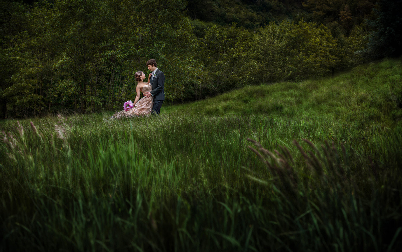 Woman sitting in tall green grass on a hillside.