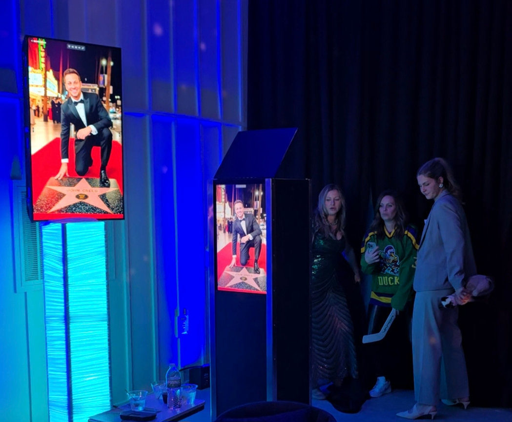 Guests viewing AI-generated portraits on the photo booth display during a live event.