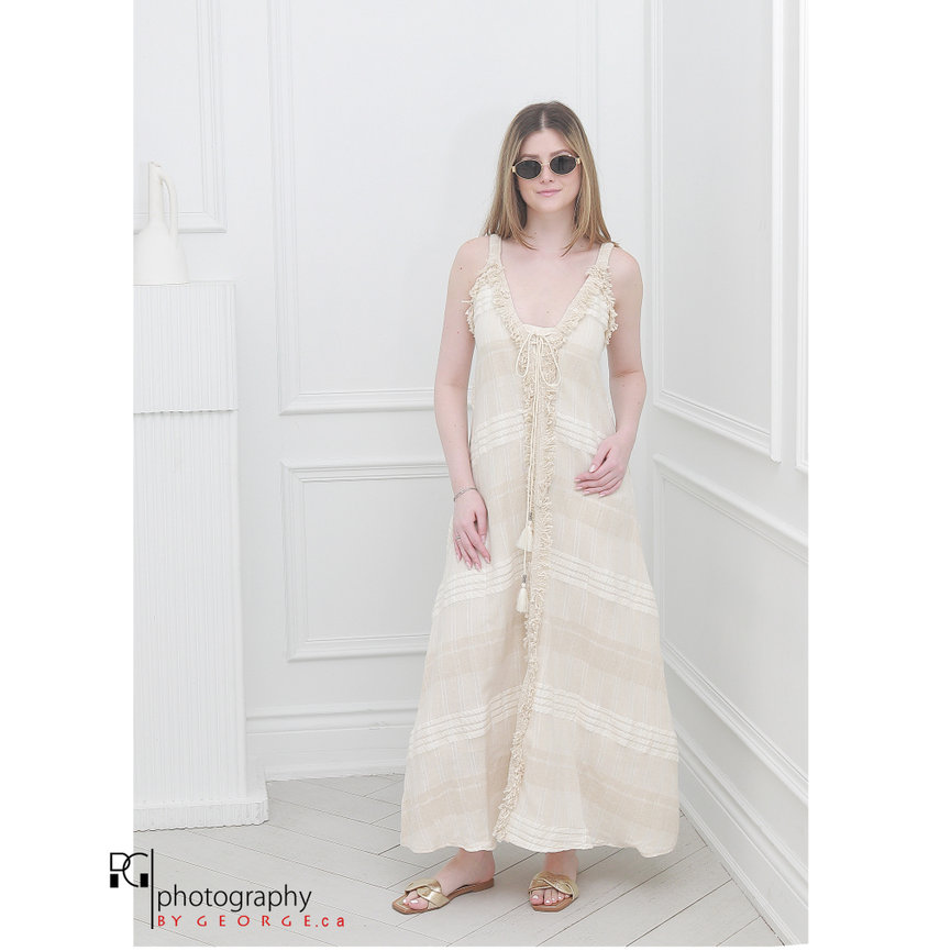 Model wearing a cream bohemian linen maxi dress with fringe details, showcasing Summer 2026 resort fashion trends.