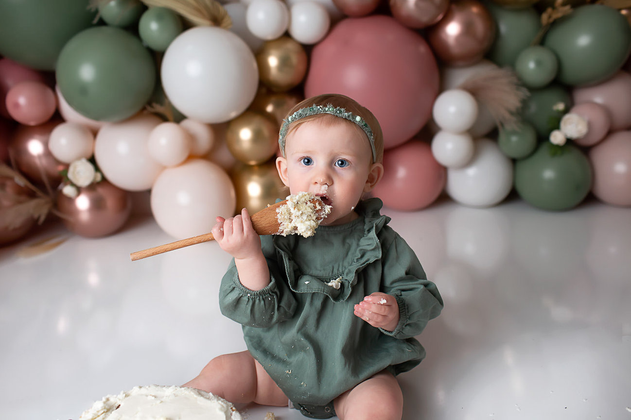 baby eating cake of a spoon during cake smash photography session in Kansas City with cake smash photographer Dreamworks Photography