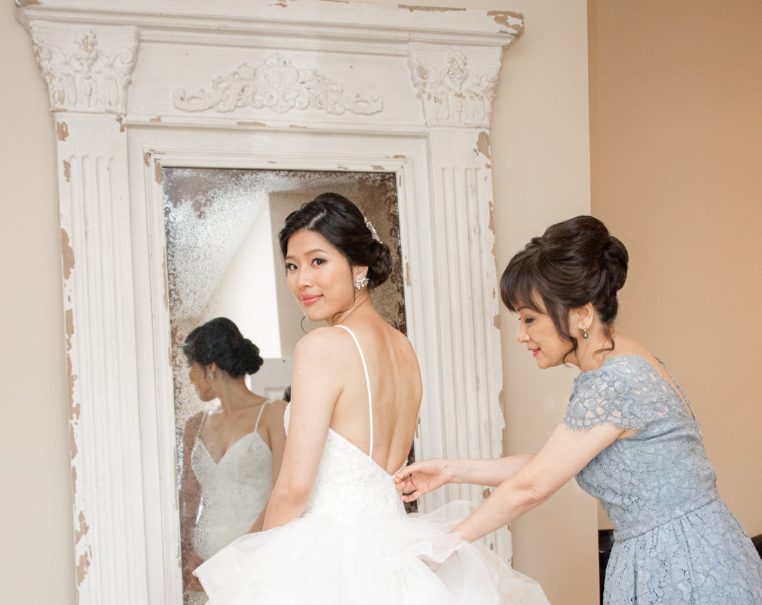 Bridesmaids helping the bride into her wedding gown before the ceremony