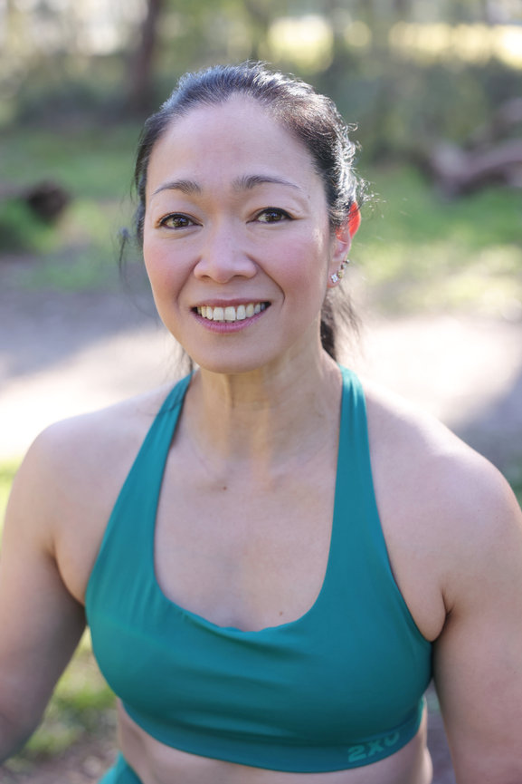 Smiling woman in teal sports bra outdoors in a sunny park. authentic photos for my business and website