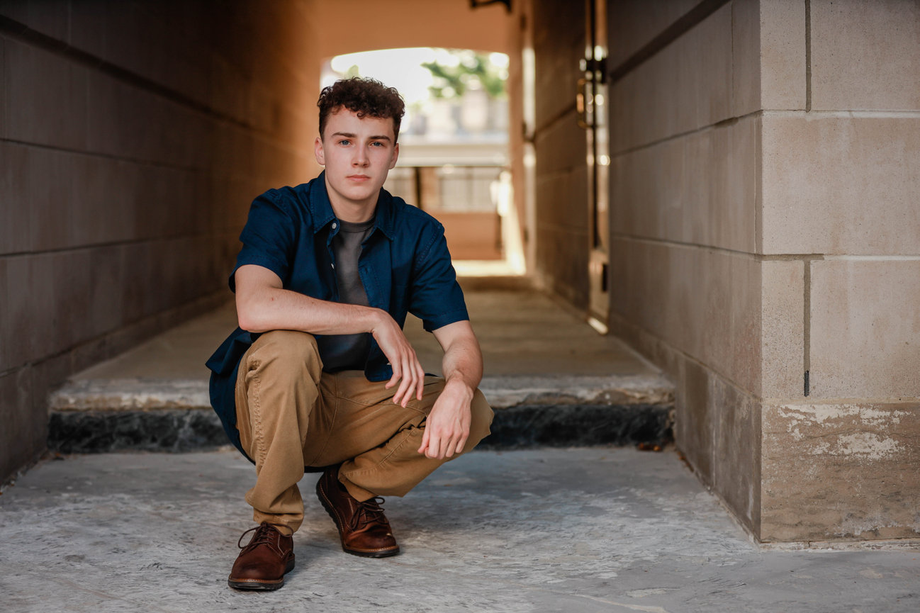 Senior boy posed low to the ground in alley backdrop