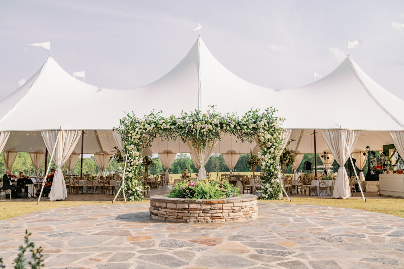 Private farm wedding with sailcloth tent covered in florals. Wedding photography by Heather Durham.