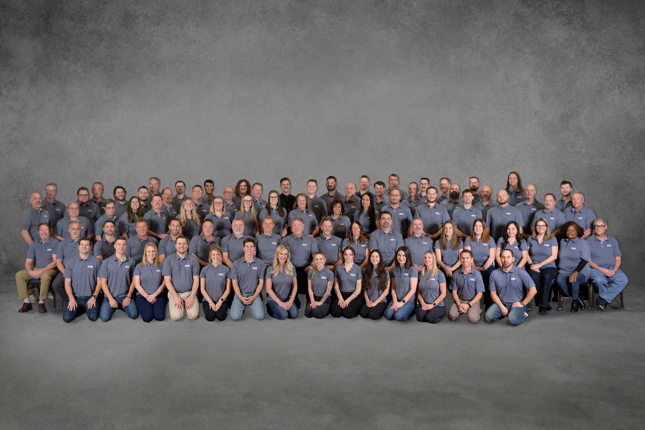 A photograph of a 80 person work team wearing gray.
