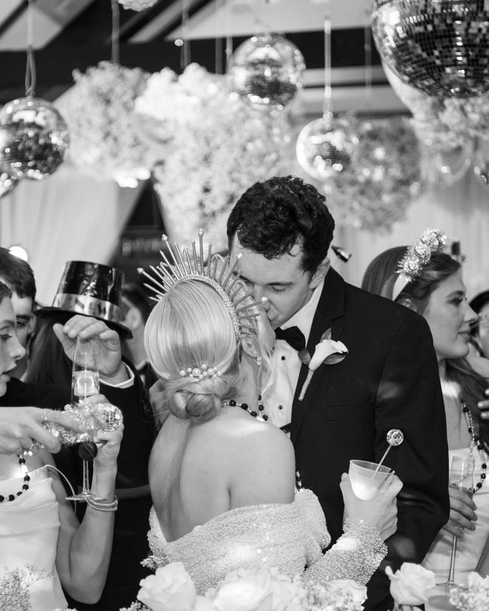 Black and white image of bride and groom kissing at midnight during their New Years Eve wedding reception. Alabama wedding photography by Heather Durham.