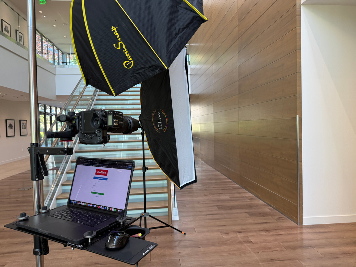 Camera setup with laptop, lights, and tripod in a modern indoor stairwell