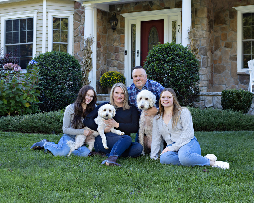 Outdoor family portrait in front yard of family home with two dogs