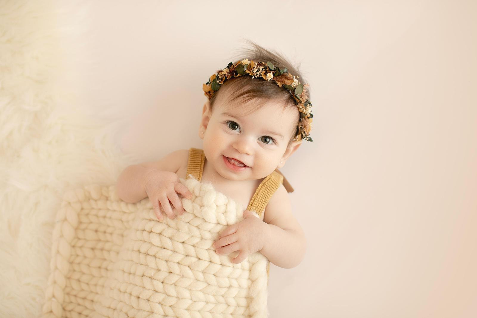 Baby peeking around a woven basket against a cream backdrop
