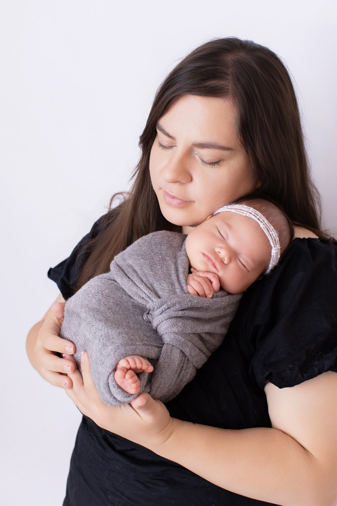 Mother holding her sleeping newborn daughter close in a Calgary studio