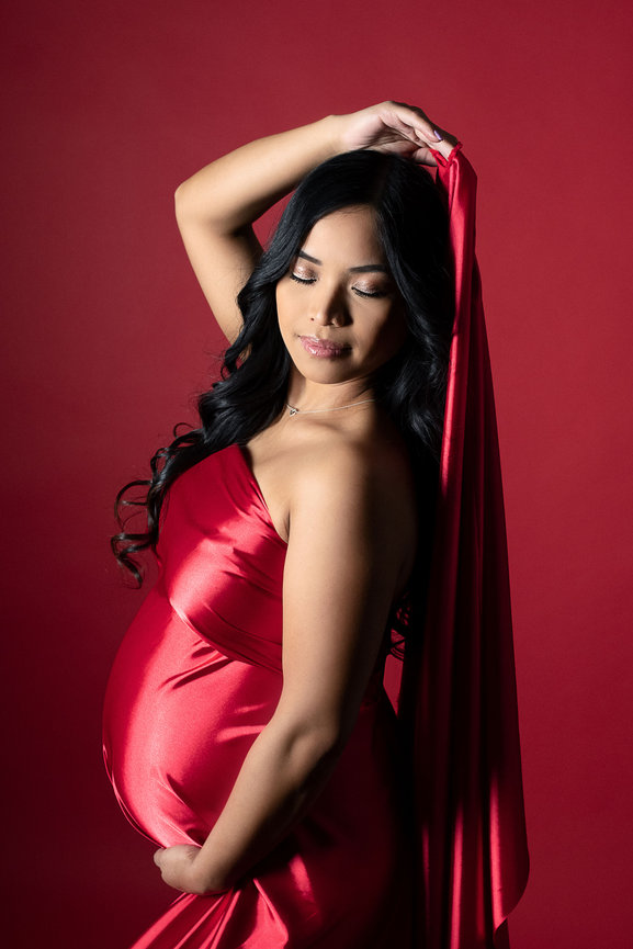 Mom pregnant with baby in red material on a red background