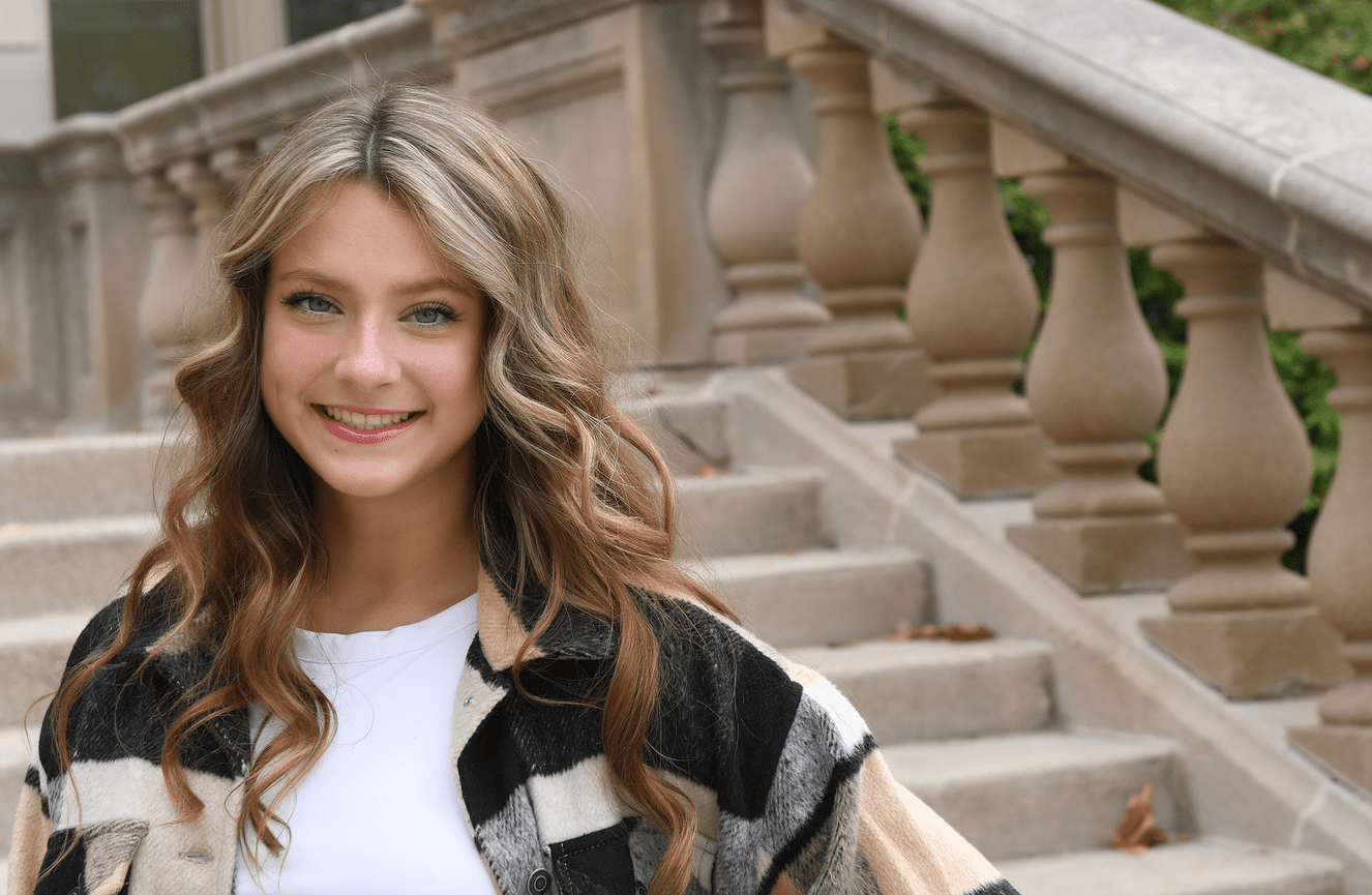 A young gal in wavy hair poses outside on the University of Iowa campus.