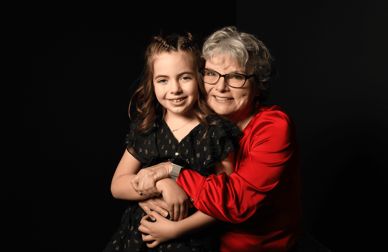 A grandmother wrapping her arms around her granddaughter as they celebrating her 75th birthday.