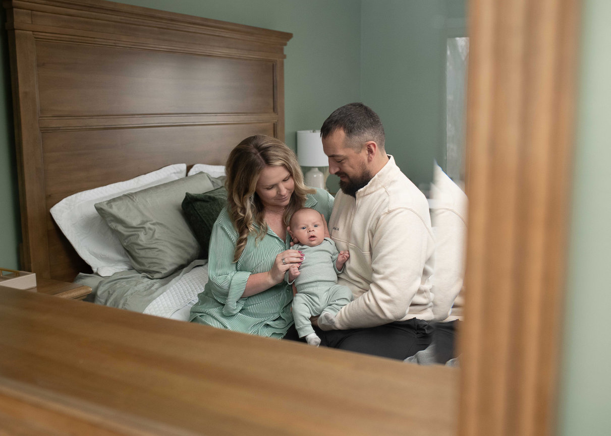 Parents holding their baby on a bed in a cozy bedroom