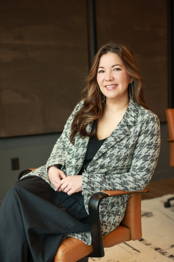 Smiling woman in patterned blazer seated in a modern office chair