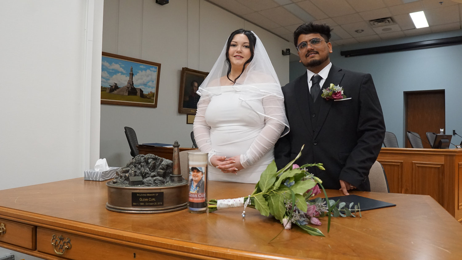 Bride and groom standing by a table with bouquet in ceremony room